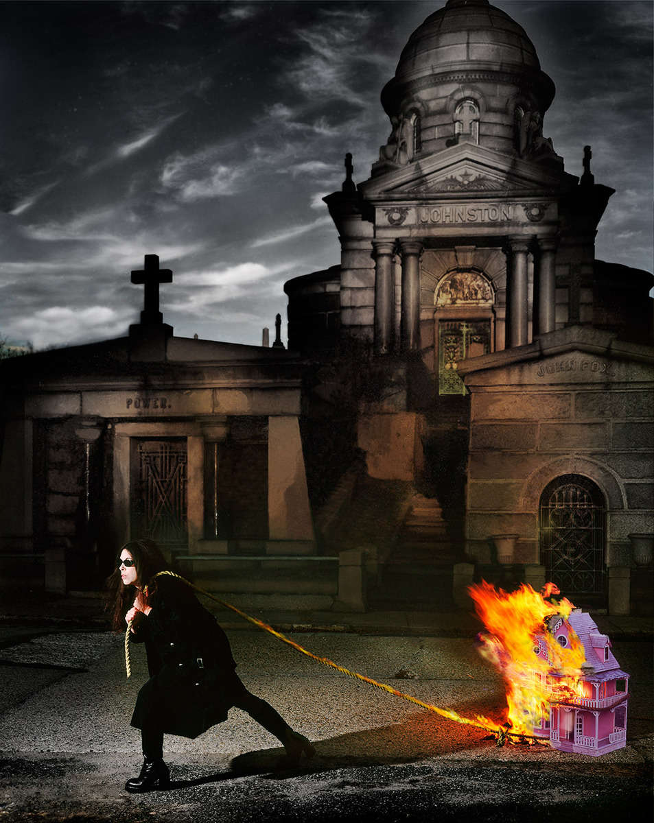 Raven Schlossberg Collage Artist with burning doll house shot on location in the Calvert Cemetary, Greenpoint, NY.